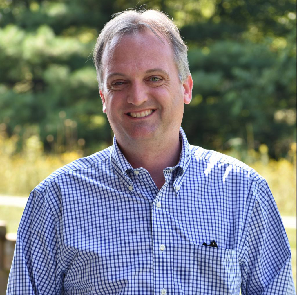 Admissions Director Alex Jackson smiling in front of greenery