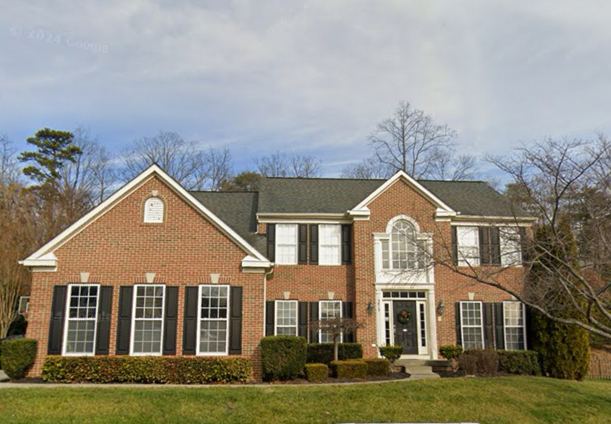 Large two-story brick home with black shutters and manicured front lawn belonging to the Agency operated group home named Deep Creek in Fredericksburg, Virginia.