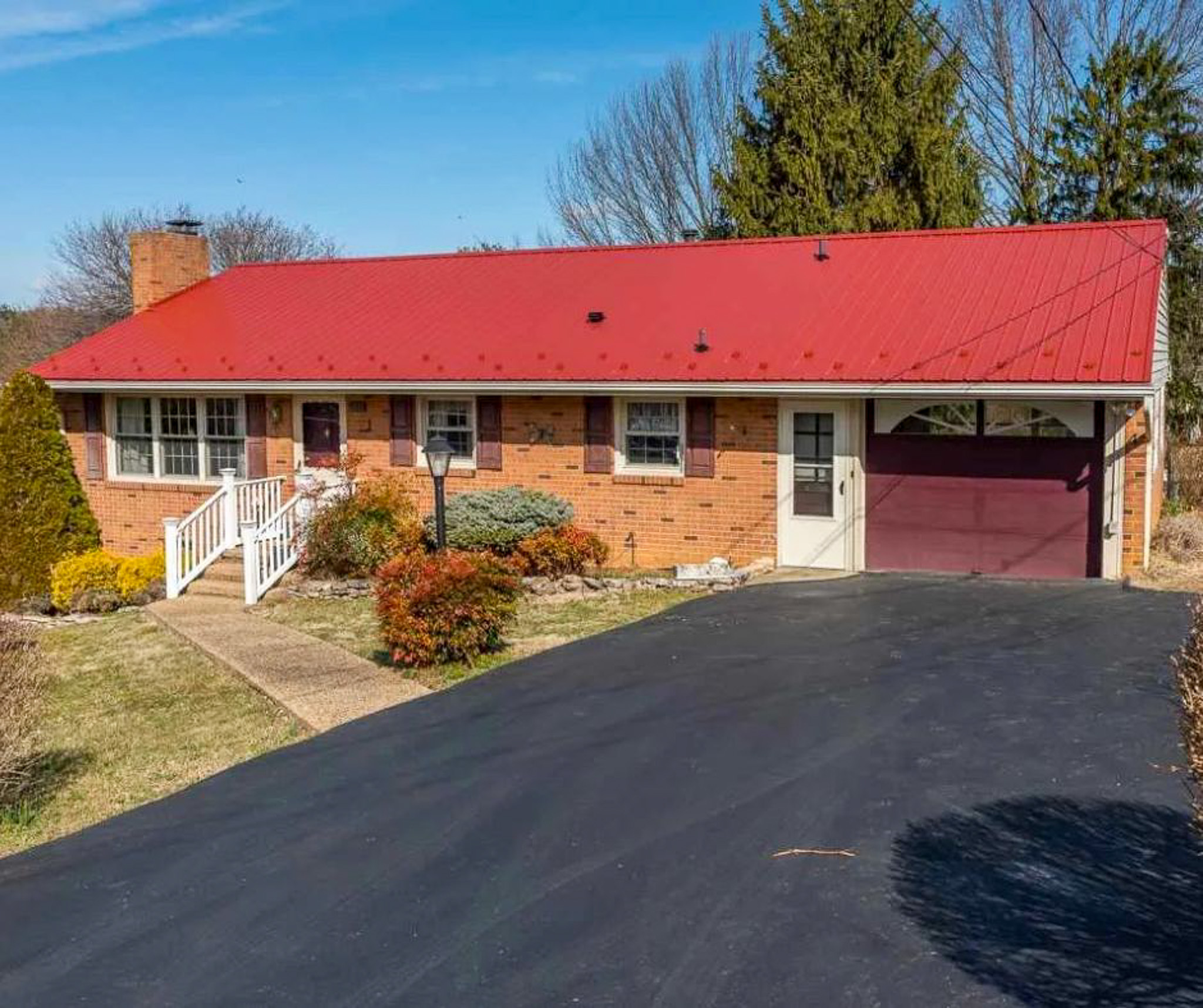 Brick one‑story house with a red metal roof, attached garage, paved driveway, and landscaped front yard belonging to Sponsored Residential Providers Bill and Heather Terry in Staunton, Virginia.