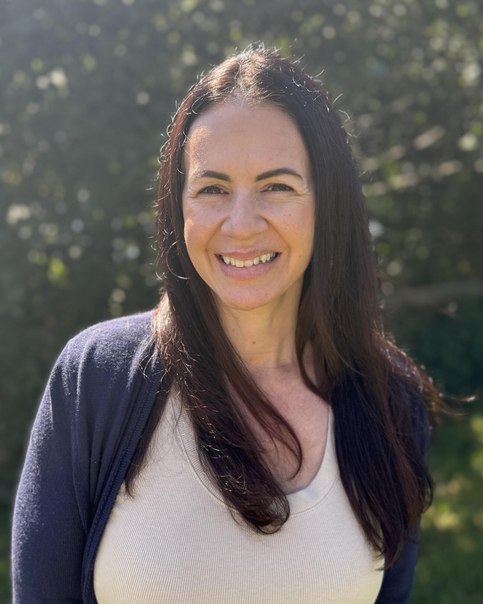Admissions Coordinator Heather Risener smiling in front of greenery
