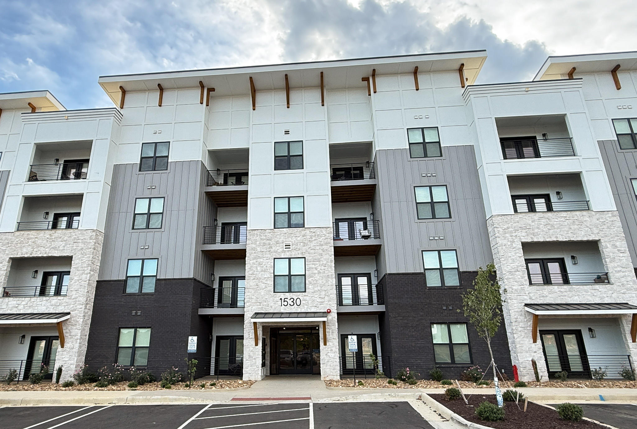 Modern multi-story condominium building with balconies, stone and gray exterior accents, and a covered main entrance where Sponsored Residential Provider Justina Megginson resides in Roanoke, Virginia.