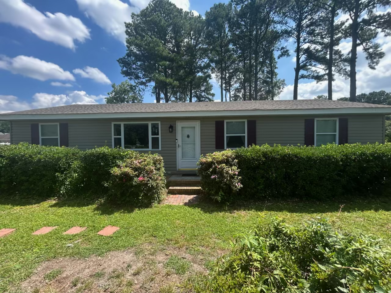Single-story gray home with a neatly maintained front yard, hedges, and tall trees in the background, home of Sponsored Residential Providers Tammy King-Neal & Gregory Neal in Chesapeake, Virginia.