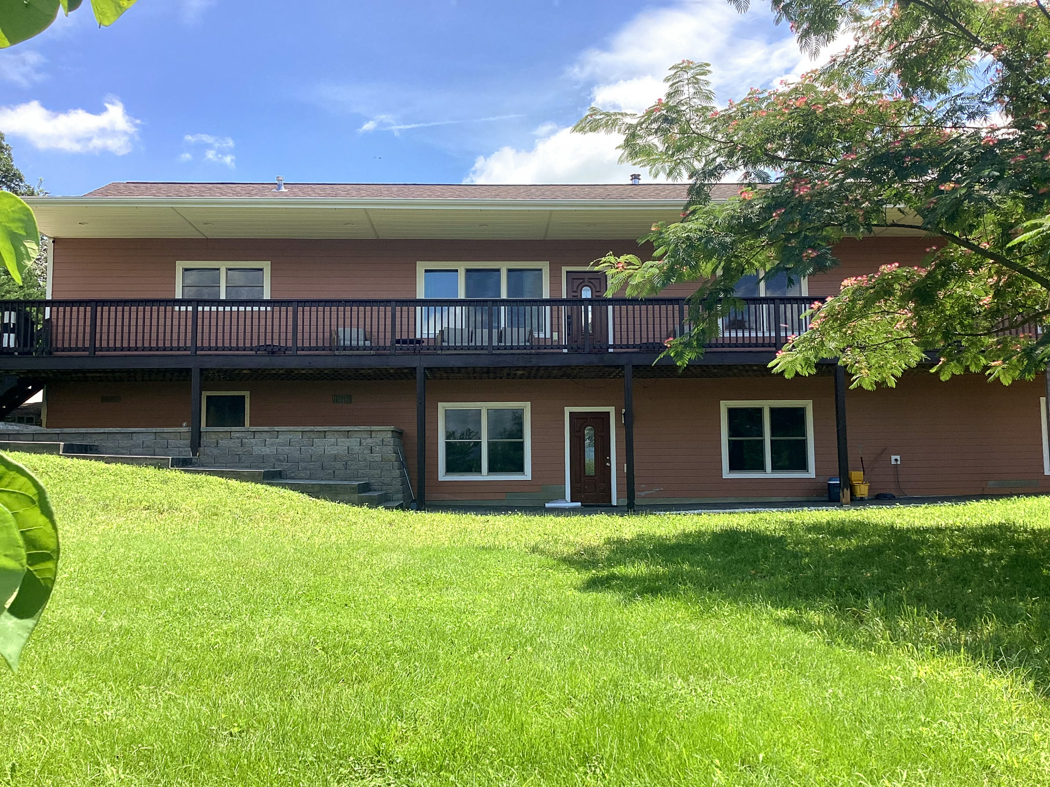 Rear exterior view of a two-story home with a large deck overlooking a grassy yard. This home belongs to Wall Group Home provider Lisa Lohr in Harrisonburg, VA.