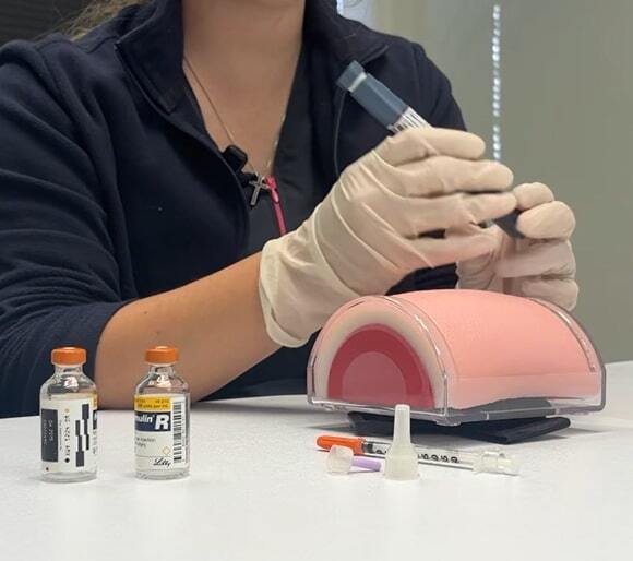 A nurse giving a demonstration on using medical equipment during a training session.