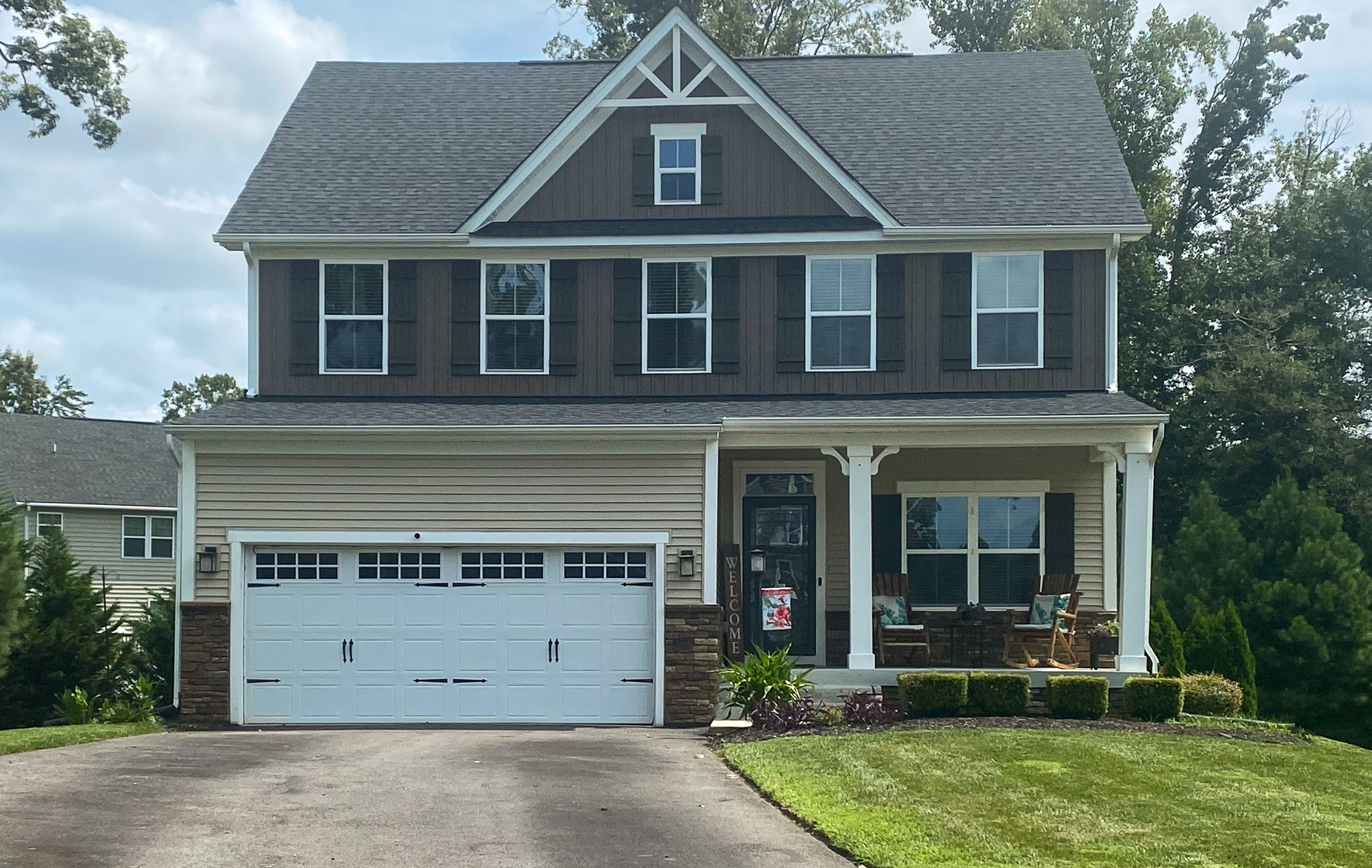 Two-story suburban house with gray roof, beige siding, white garage door, and a front porch with chairs and plants belonging to Sponsored Residential Providers Christopher and Tawanda Tedder in Richmond, Virginia.