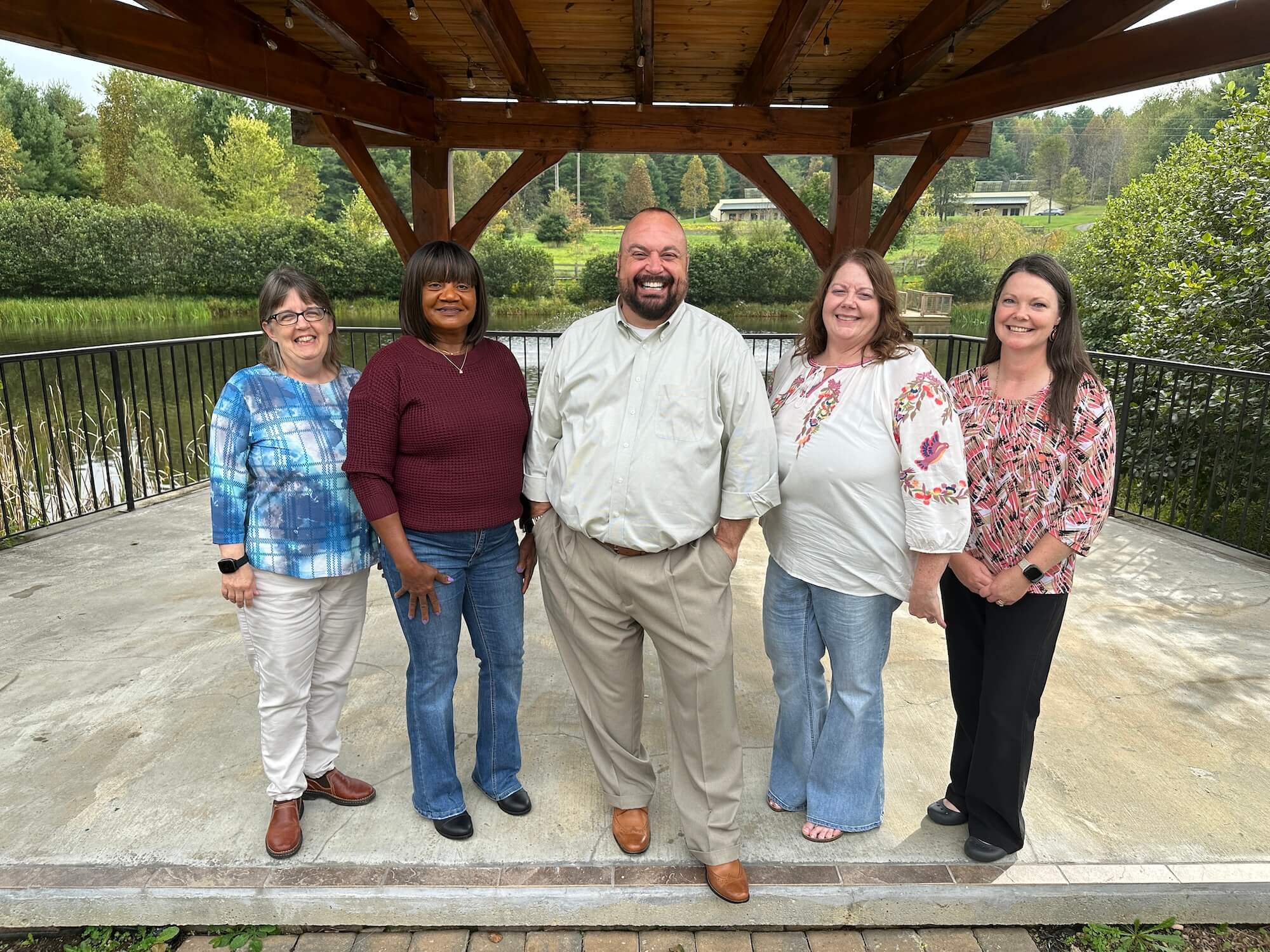 Five staff members of Wall smiling under a gazebo outside the Floyd office.