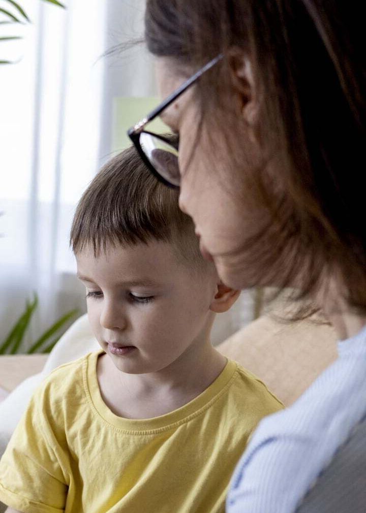 A young boy receiving home ABA therapy from a therapist using colorful toys in a red box