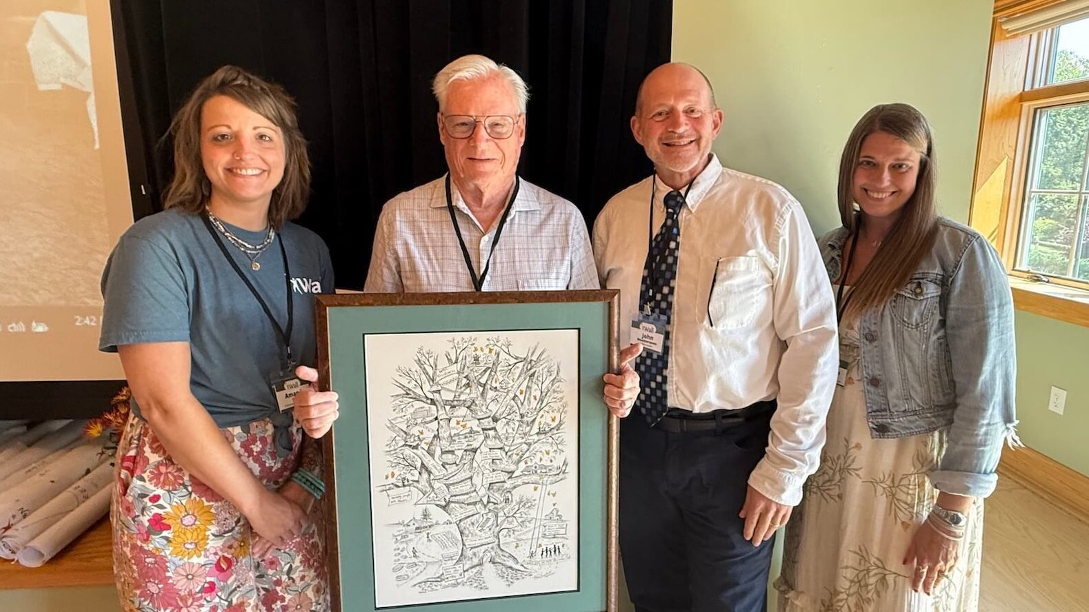 Wall leadership staff posing with gift to founder Jack Wall at Floyd office